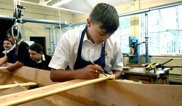 male student making a measurement mark on a piece of wood